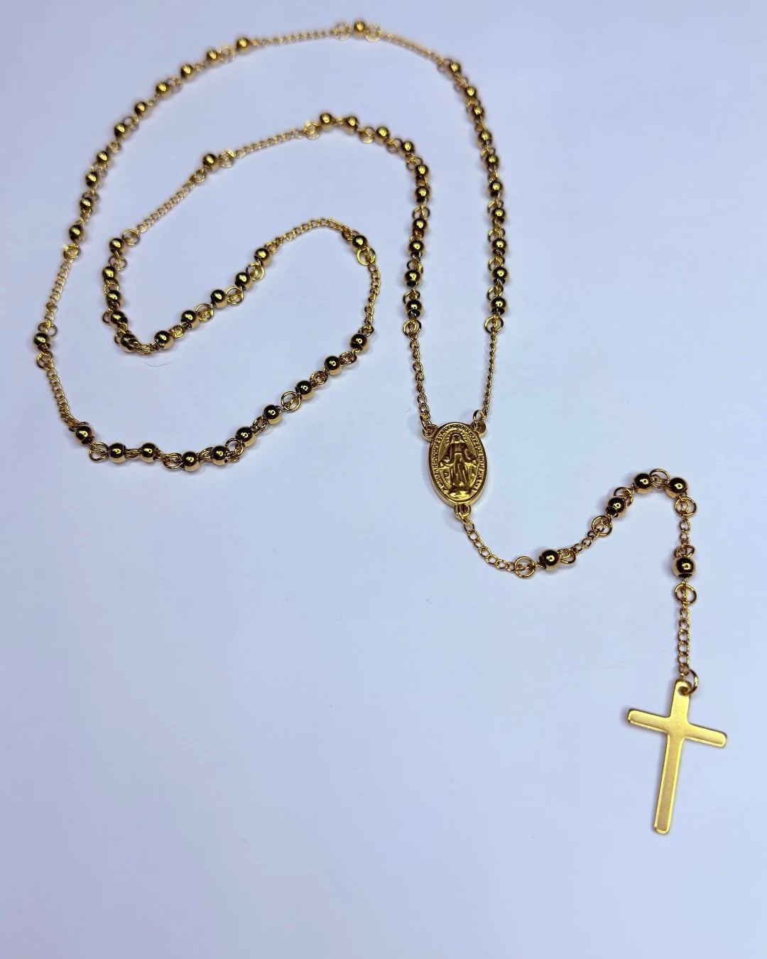 Detalle del collar rosario dorado con cruz